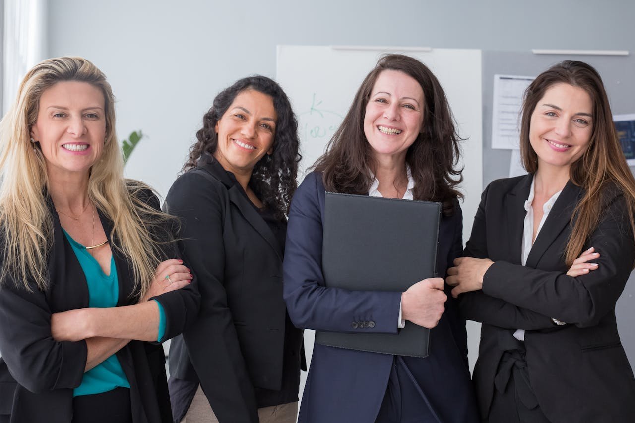 Four confident businesswomen in Portugal, smiling in professional attire, representing teamwork and success.